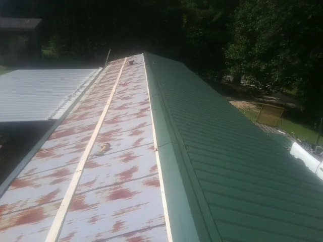 Old rusted panels beside newly installed green metal roofing — Wind Damage Roof Repair by Roofing Brothers in Champlin
