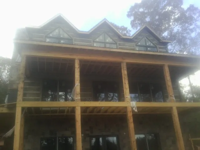 Dormers and porch framing on a large log home under construction — Roof Coating work by our crew in Champlin