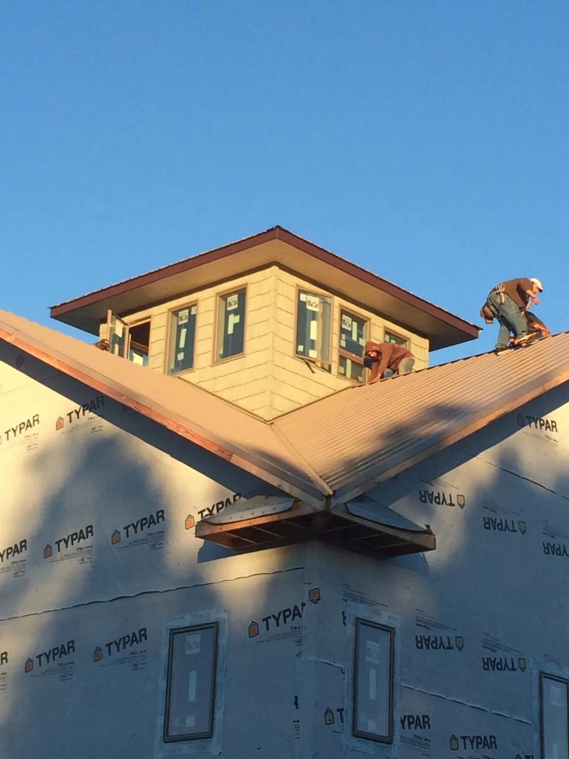 Roofers working around a rooftop cupola on a new metal roof at sunset — Roof Waterproofing in Champlin by Roofing Brothers